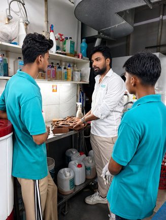Trainer explaining laundry chemicals to trainees in a processing area